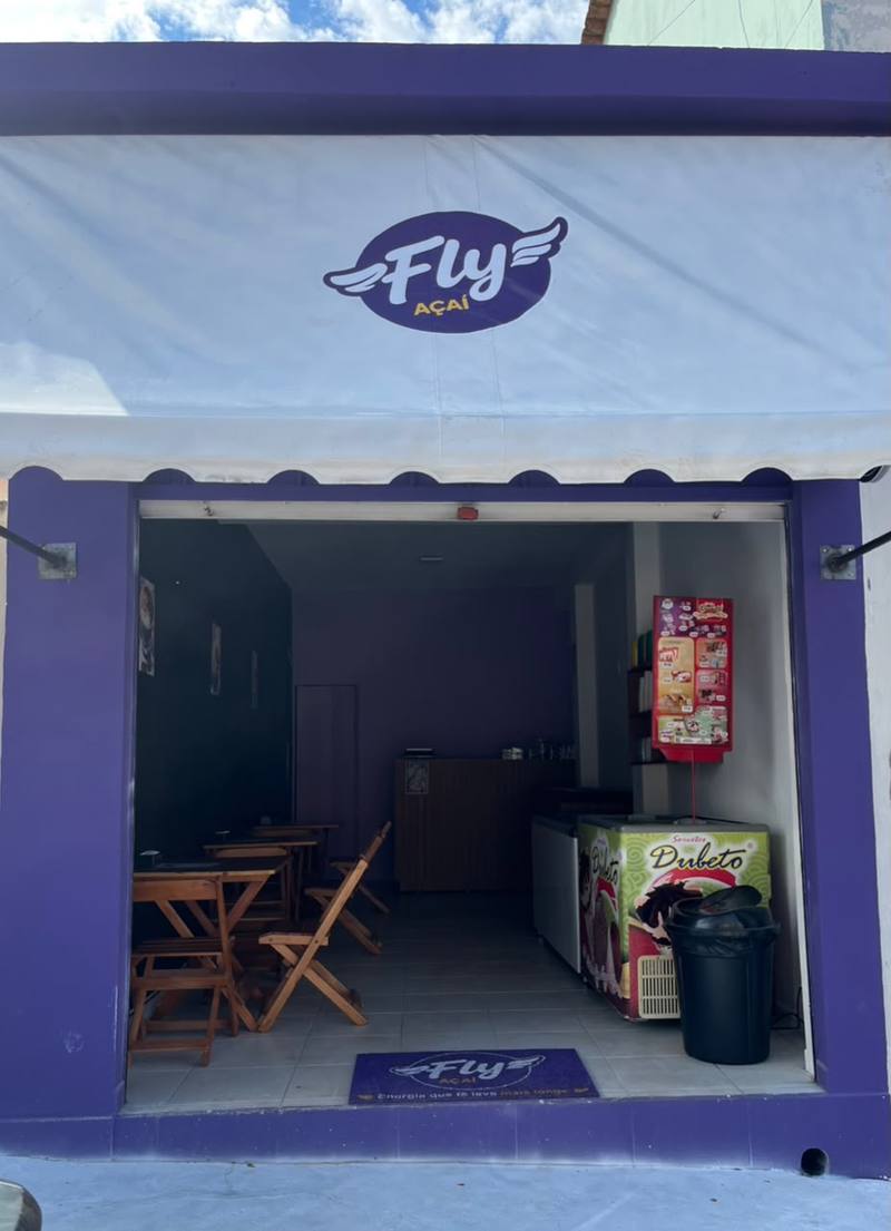Fachada da Fly Açaí, com mesas e cadeiras para comer no local